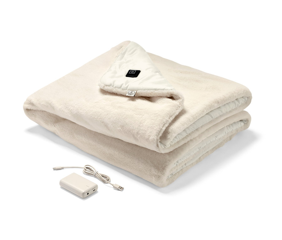 Złożone akumulatorowe poncho elektryczne w kolorze kremowym z widocznym panelem sterowania i akumulatorem.