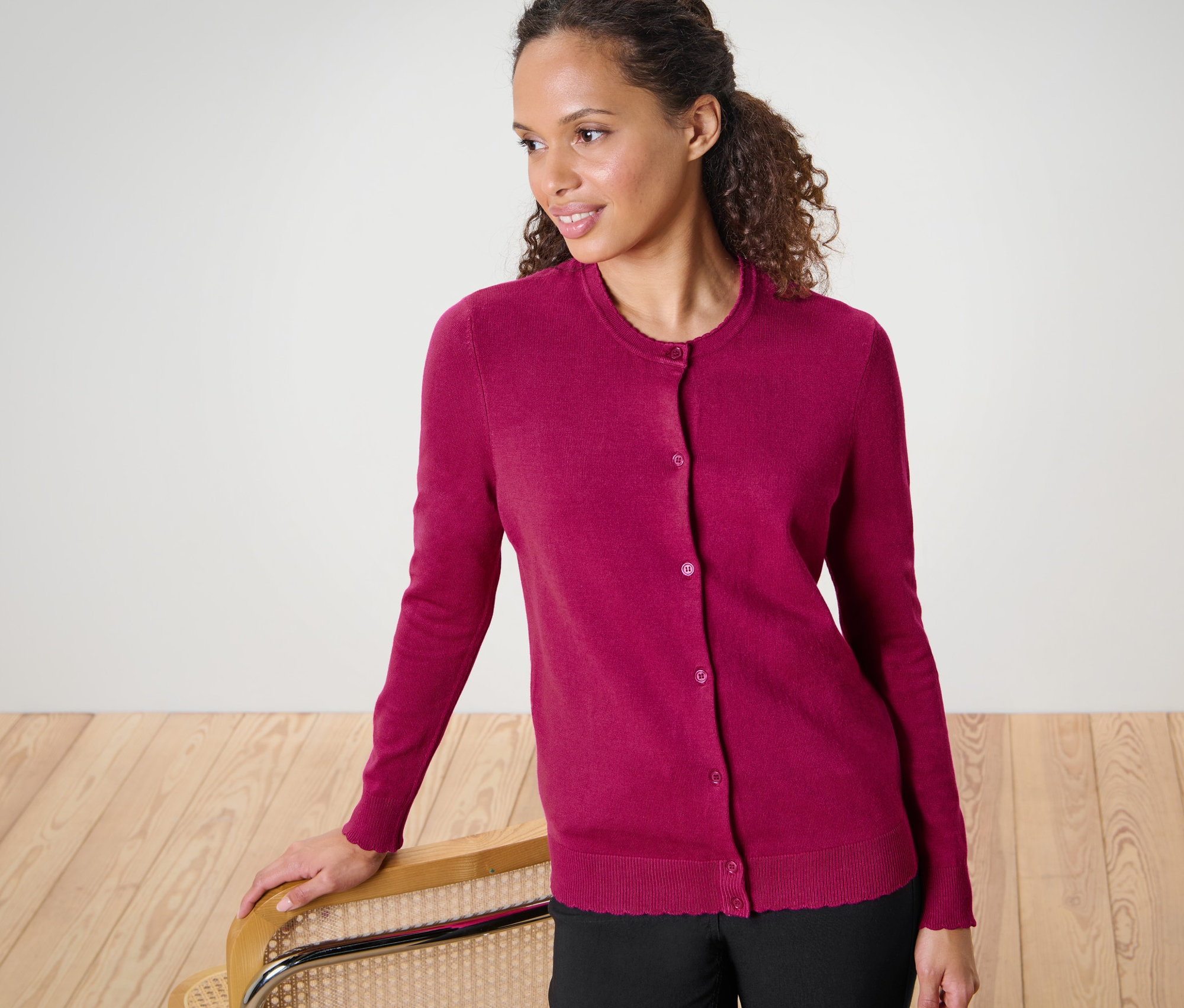 Kobieta z falowanymi włosami pozuje w kardiganie z delikatnej dzianiny z falowanym brzegiem.