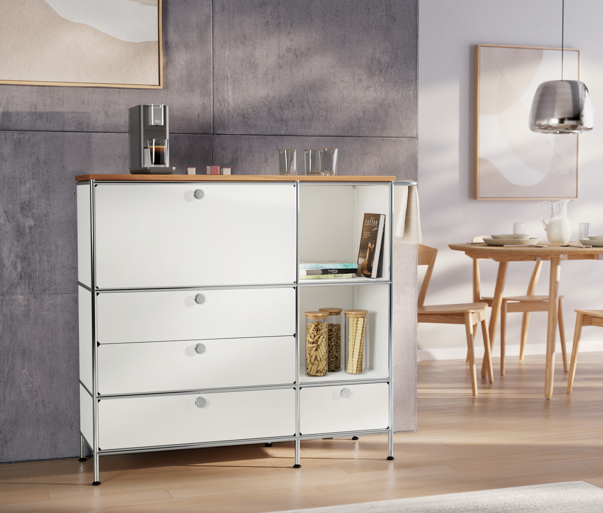 Chromowana lampa wisząca nad stołem. Komoda metalowa „CN3” biała z drewnianym blatem i ekspresem do kawy.