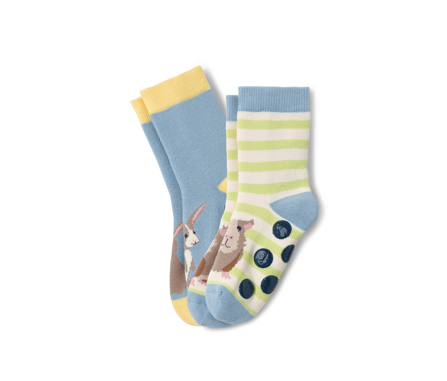 Dwie pary skarpet antypoślizgowych dla małych dzieci: jedna para jasnoniebieska z królikiem, druga w paski z świnką morską i kropkami antypoślizgowymi.