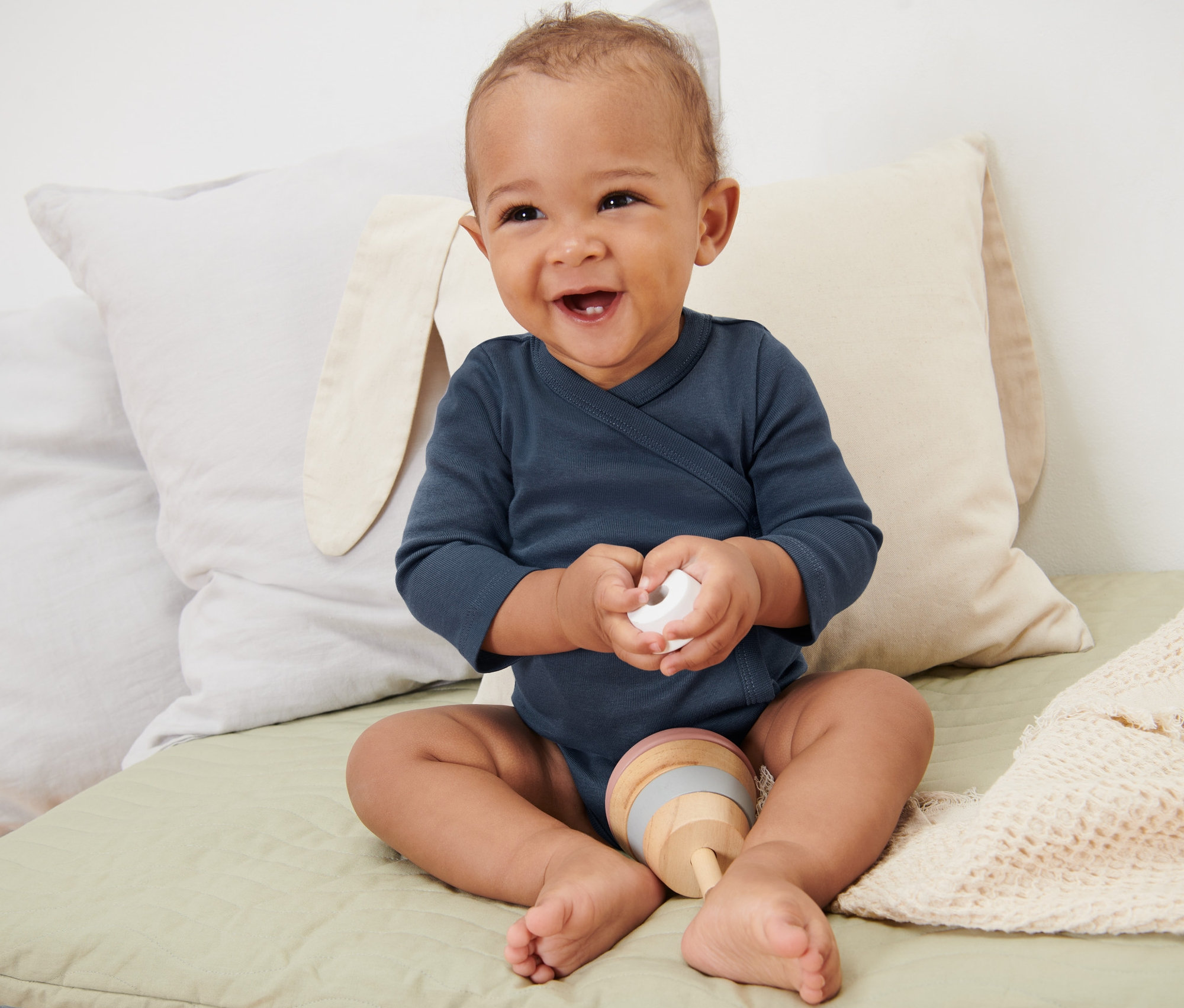 Uśmiechnięte dziecko siedzi na macie, ubrane w niebieskie body niemowlęce rosnące z dzieckiem, 5 par.