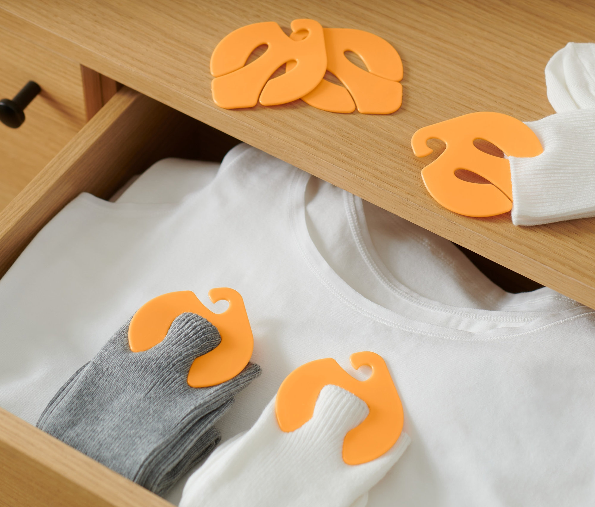 W szufladzie leży biała koszulka i skarpety połączone klipsami do skarpet, 20 sztuk.