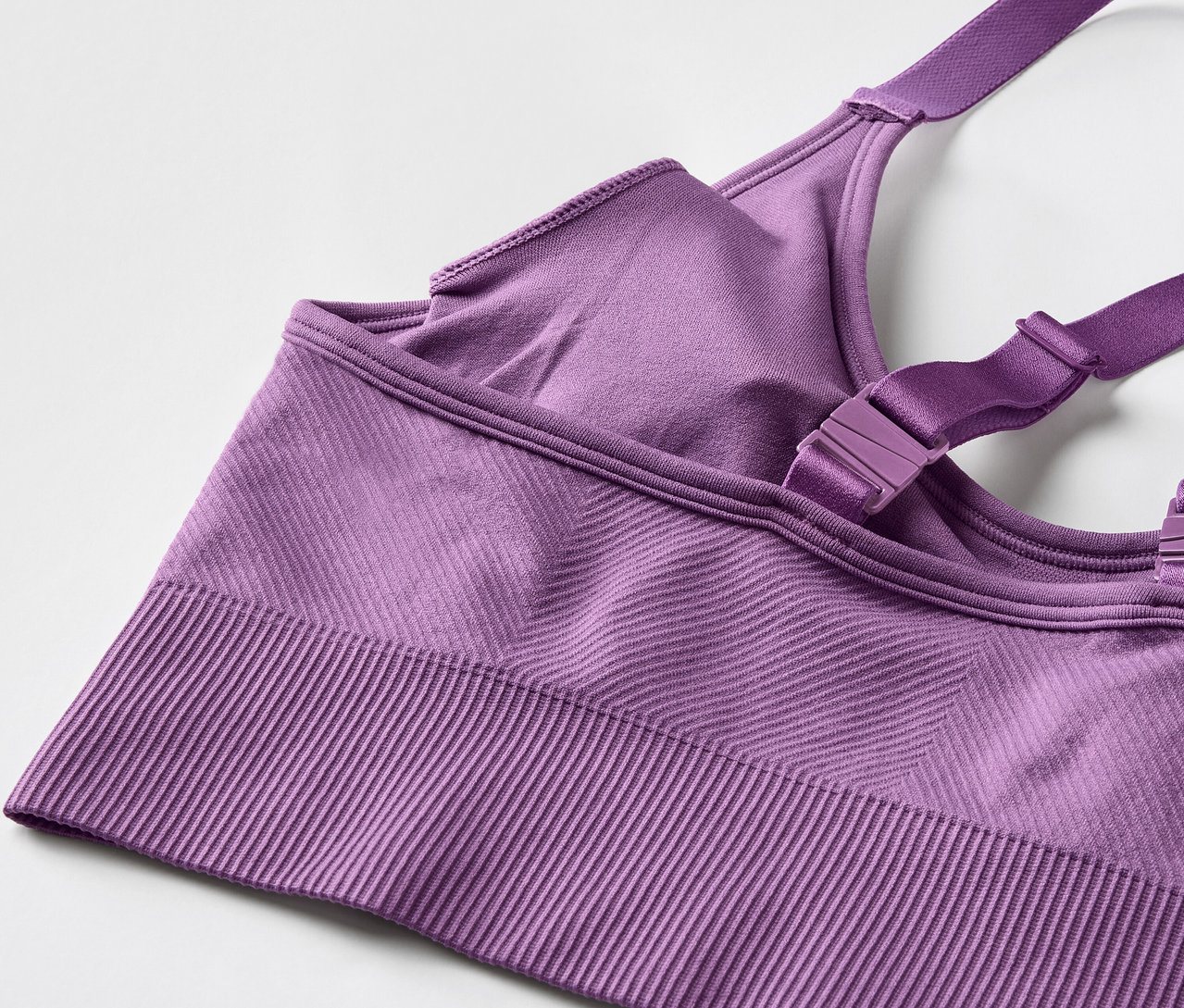Zbliżenie fioletowego biustonosza sportowego z regulowanymi ramiączkami.