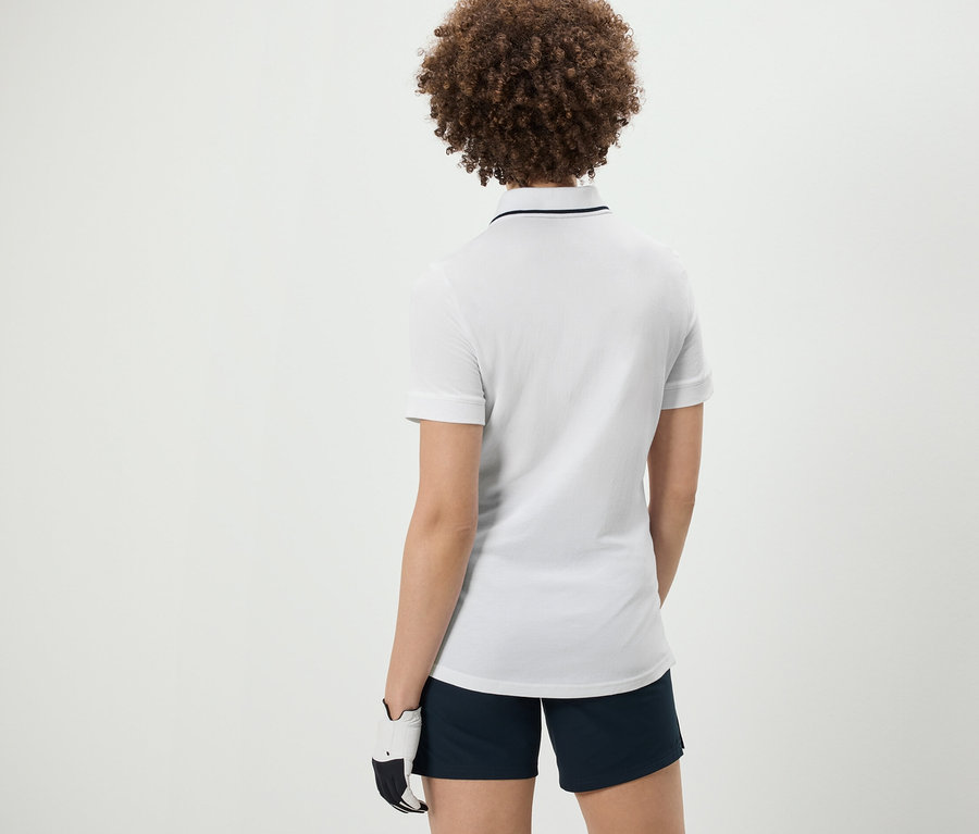 Widok z tyłu na kobietę z kręconymi włosami w białej funkcyjnej koszulce polo.