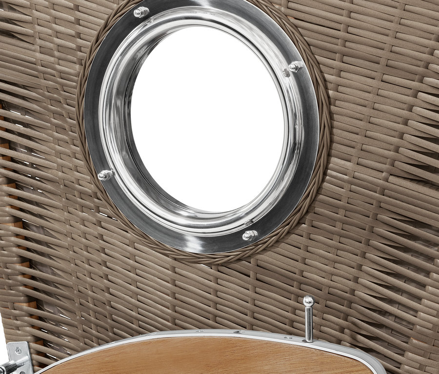 Detal wiklinowego kosza plażowego z okrągłym oknem z metalową ramą.