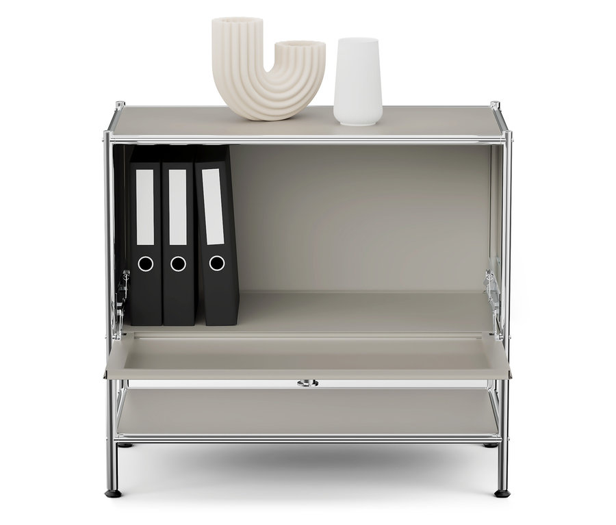 Szara szafka z chromowaną ramą, na górnej półce dwa białe wazony, a w górnej komorze trzy czarne segregatory.