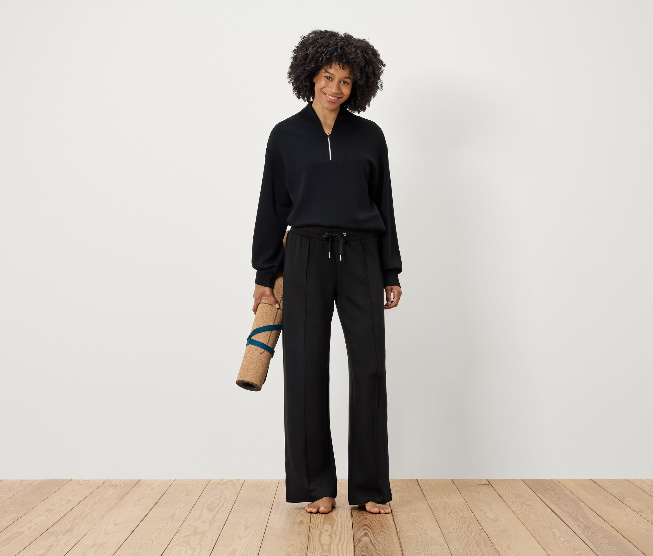 Kobieta trzyma matę do ćwiczeń w czarnym stroju.