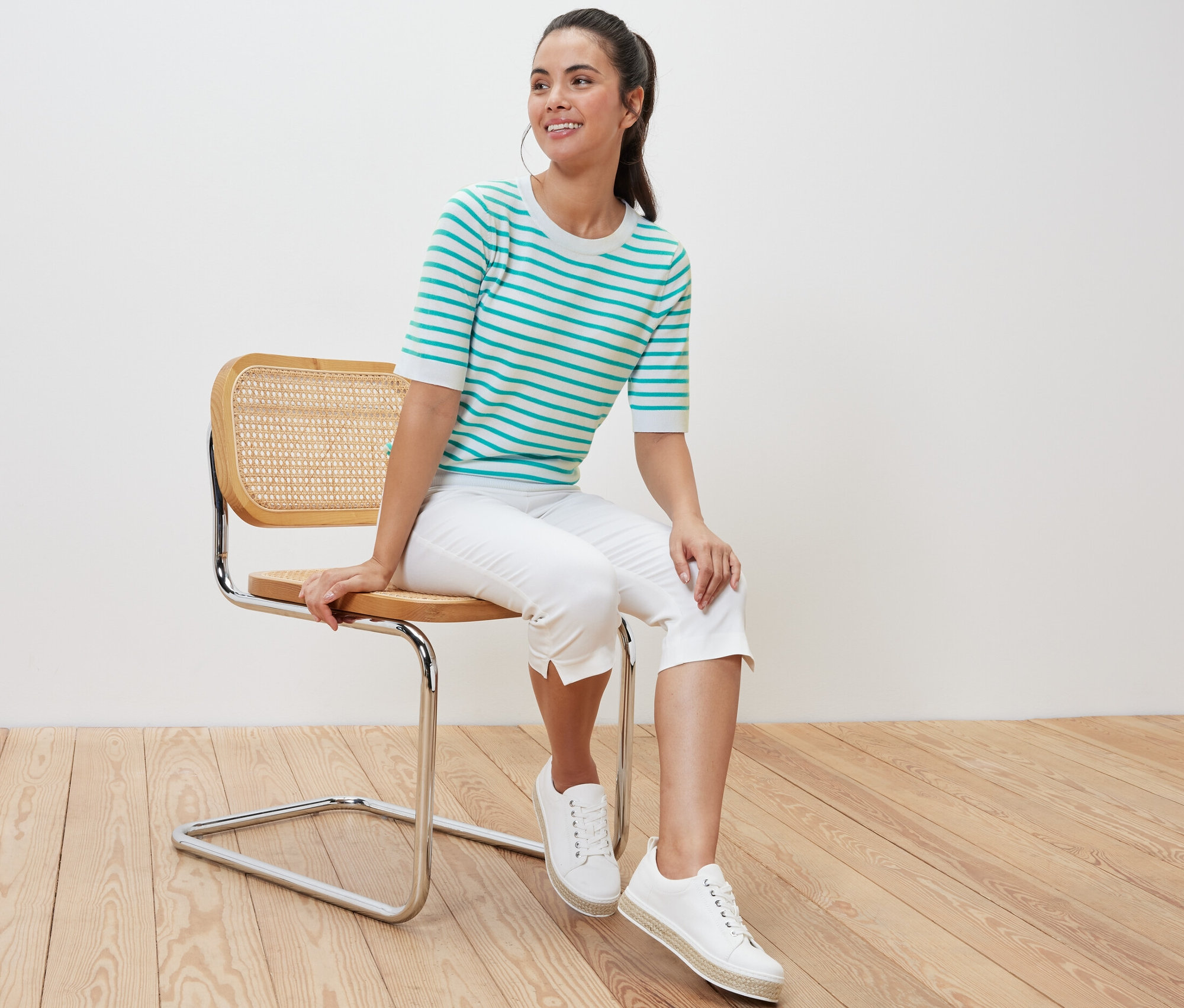 Kobieta siedzi na krześle i ma na sobie cienki sweter w paski, morski.