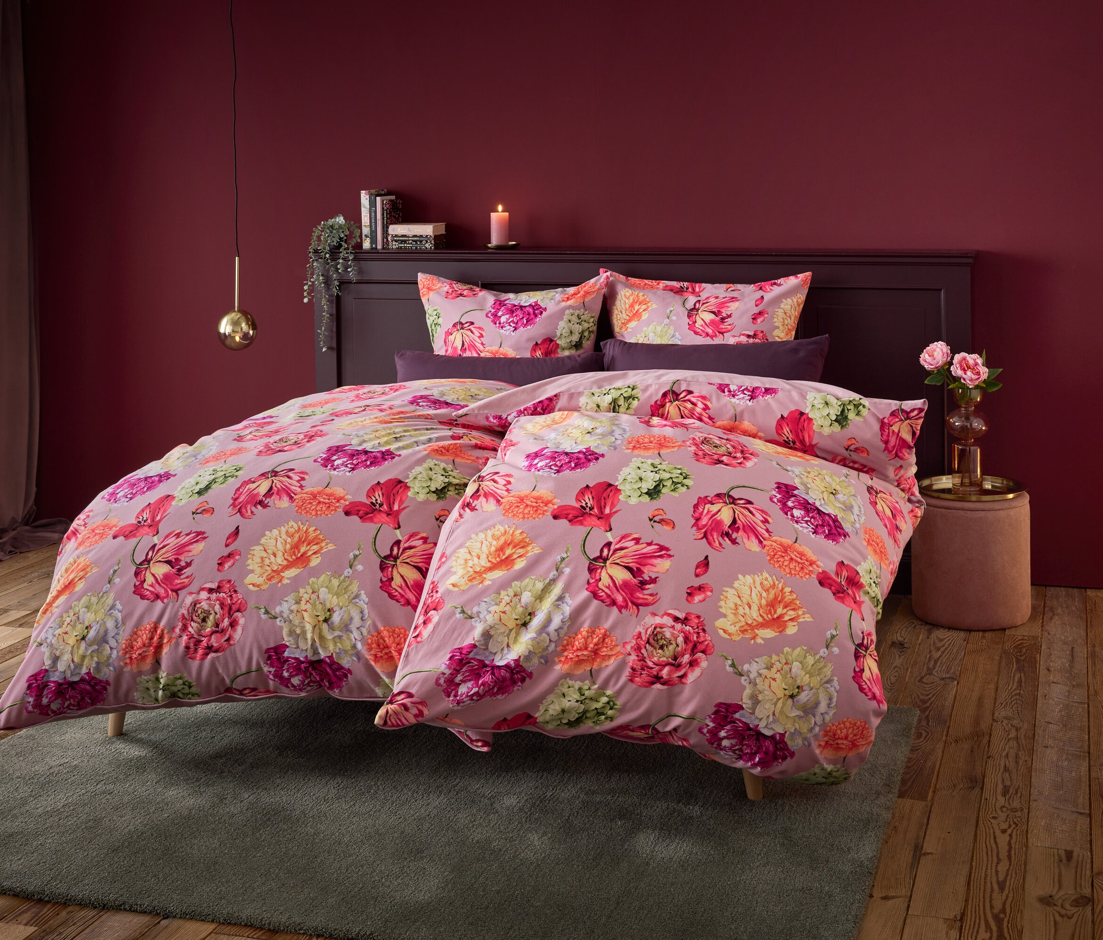 Kwiatowa pościel na łóżku z ciemnoczerwoną ścianą w tle.