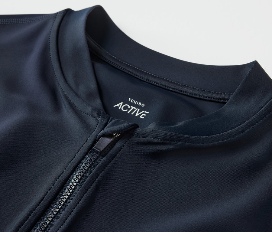 Zbliżenie na koszulkę sportową z filtrem UV, z częściowo rozpiętym zamkiem błyskawicznym.