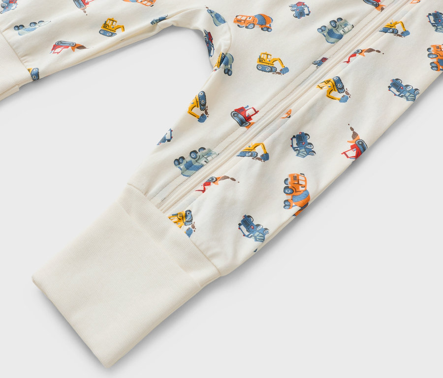 Zbliżenie kombinezonu z długim rękawem, zapinanego na zamek błyskawiczny, z motywem pojazdów budowlanych.