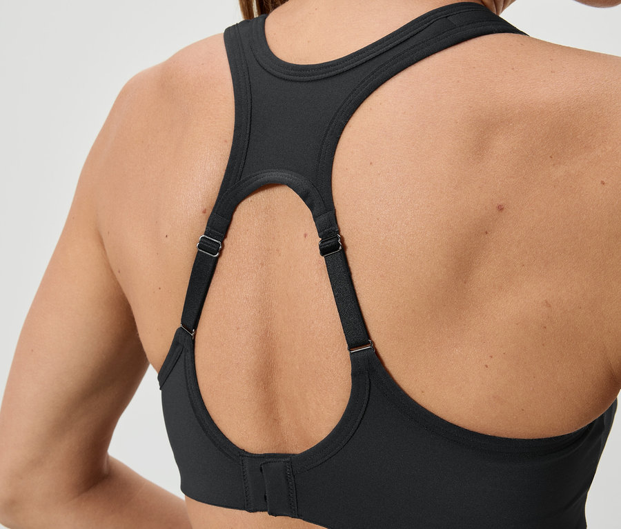 Zbliżenie na tył kobiety ubranej w czarny biustonosz sportowy z regulowanymi ramiączkami.