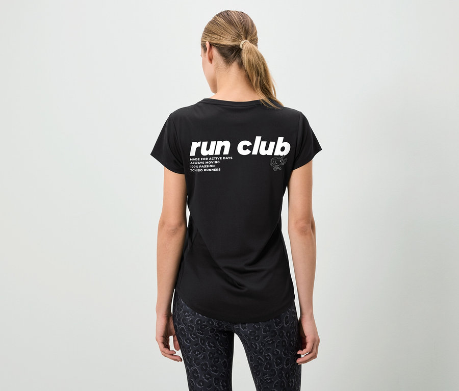 Widok z tyłu kobiety w czarnej koszulce z napisem "run club" i wzorzystych legginsach, z włosami związanymi w koński ogon.