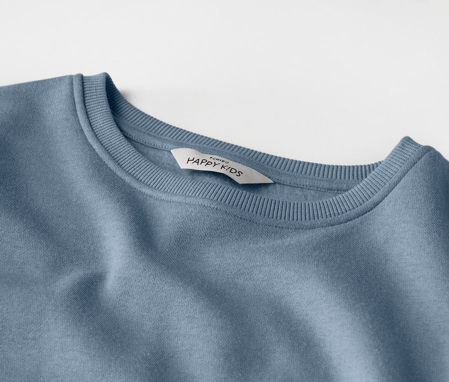 Zbliżenie jasnoniebieskiej bluzy dziecięcej z etykietą z napisem "HAPPY KIDS".