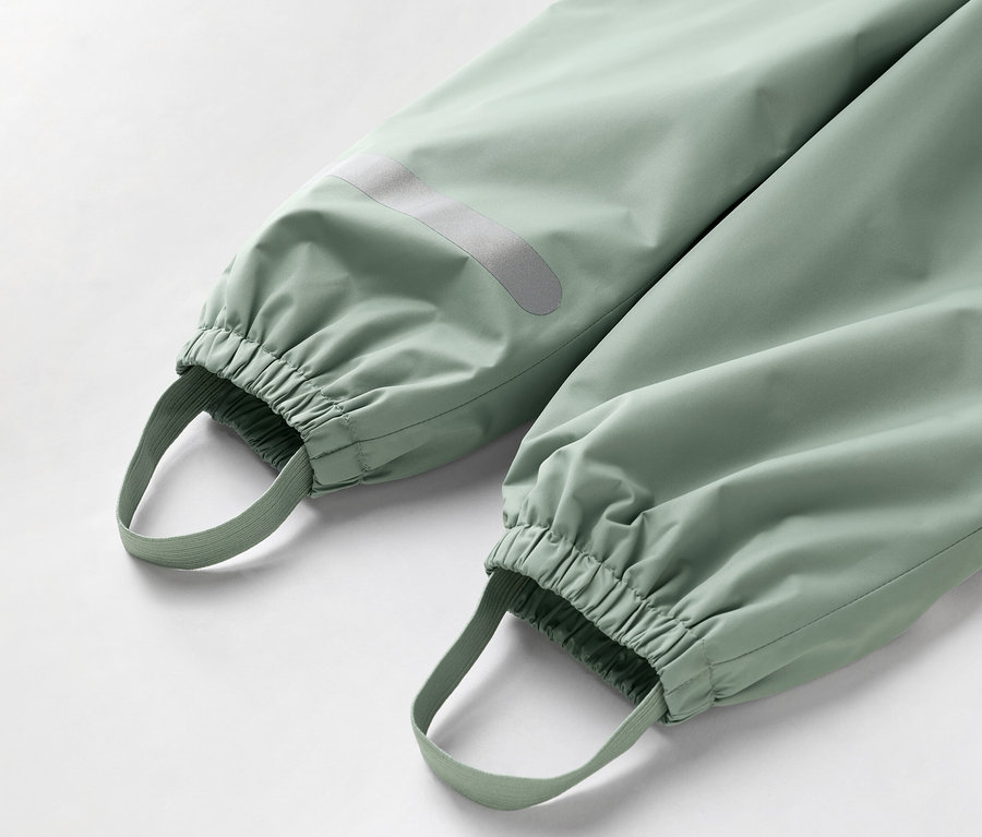 Zbliżenie dolnej części jasnozielonych spodni z elastycznymi mankietami i pętelkami na stopy.