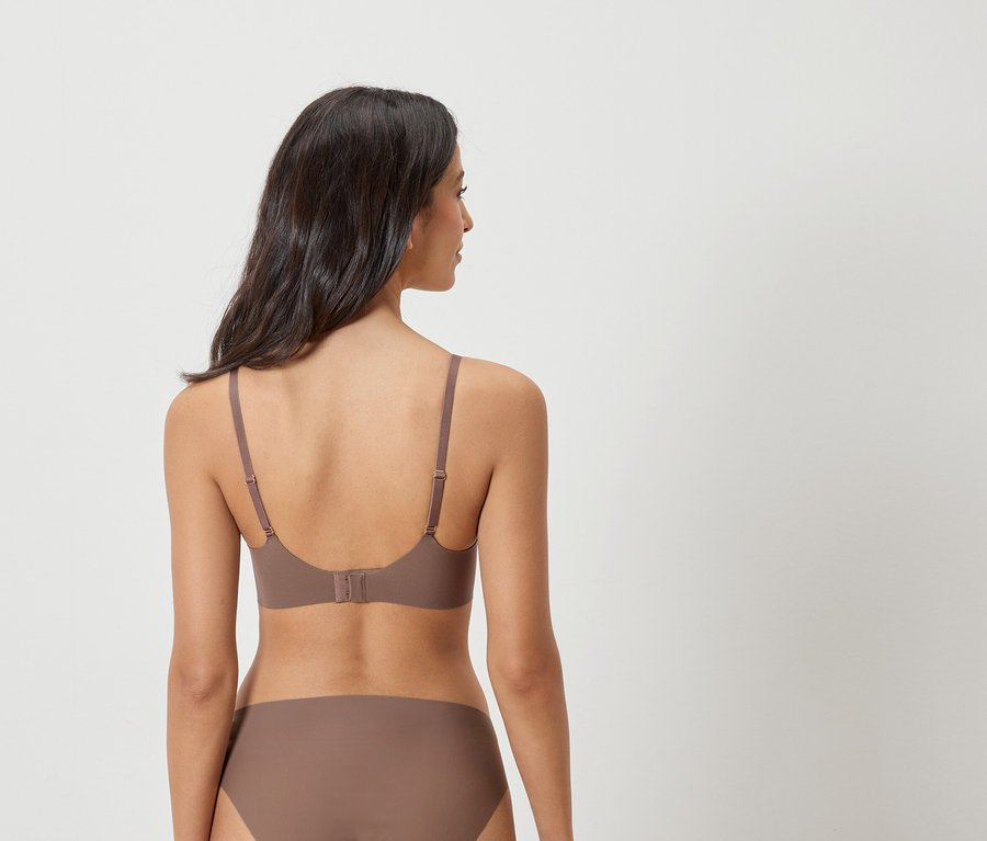 Widok z tyłu kobiety o ciemnych włosach, ubranej w brązowy biustonosz i majtki.