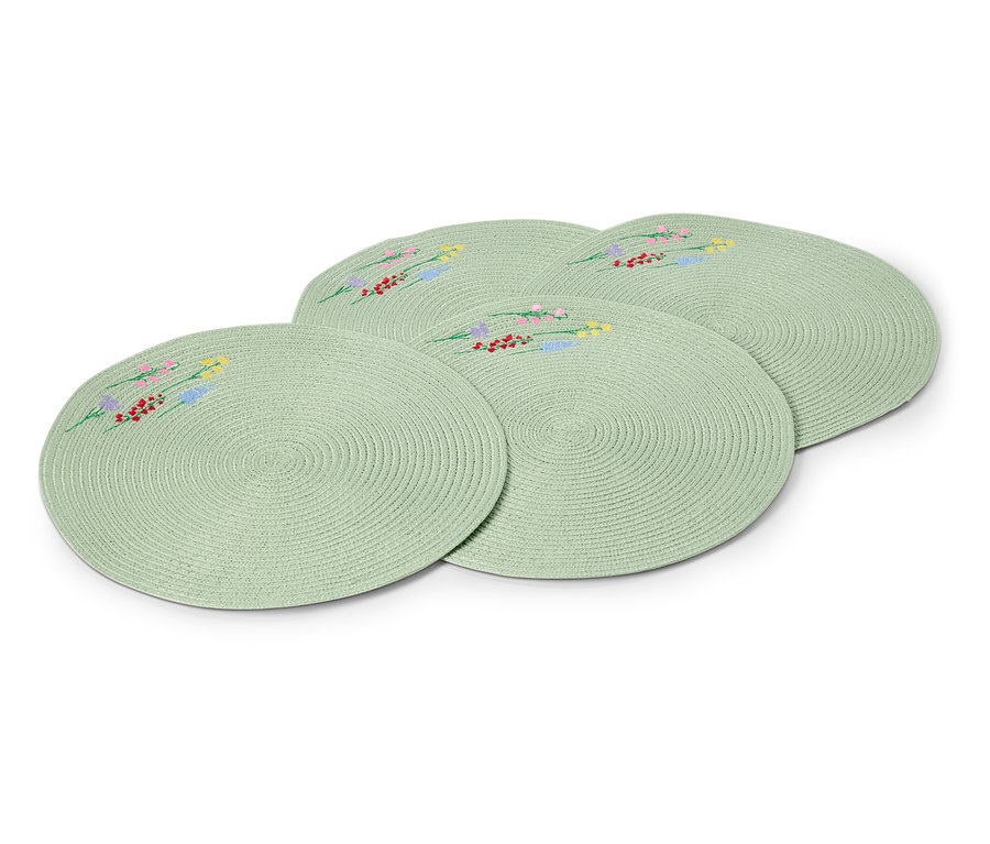 Cztery okrągłe, jasnozielone podkładki na stół z haftowanymi wzorami kwiatowymi ułożone jedna na drugiej.
