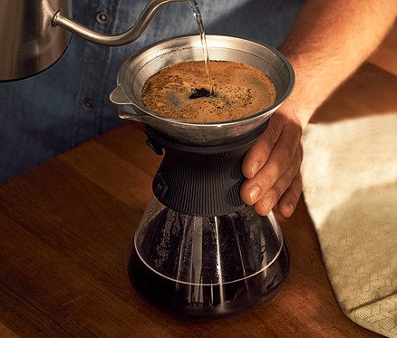 Mężczyzna nalewa wodę do szklanej karafki BEEM Pour Over 0,75 l z filtrem do kawy.
