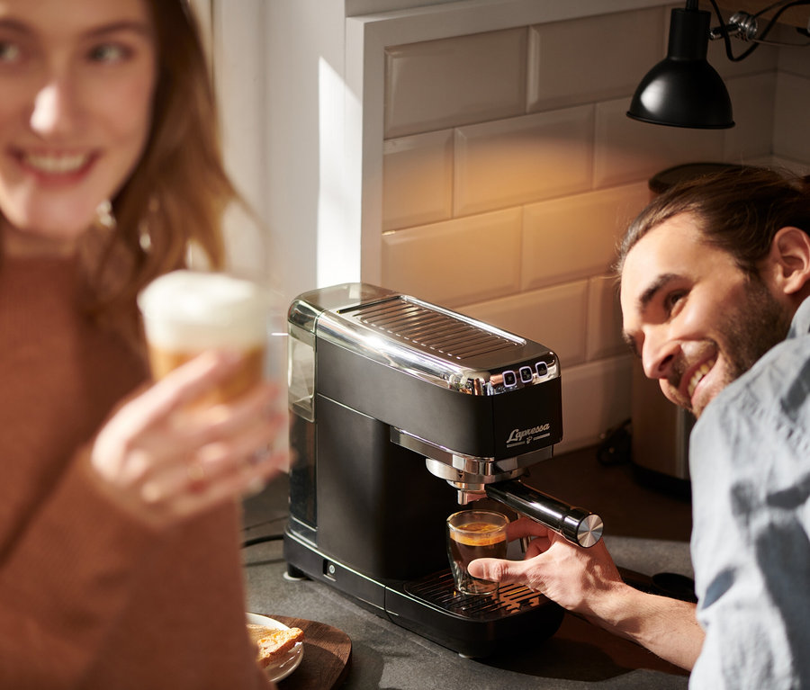 Mężczyzna robi espresso na czarnym ekspresie kolbowym do kawy »Lapressa«, kobieta trzyma latte.