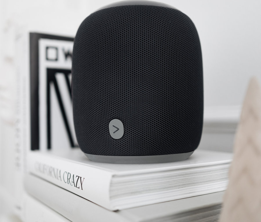 Czarny głośnik Fabric Bluetooth® stoi na dwóch białych książkach.
