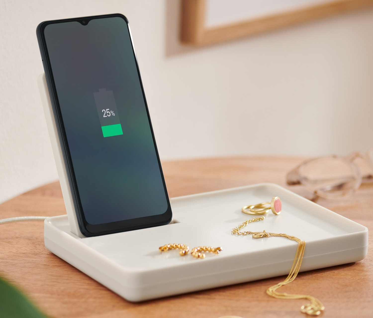 Telefon komórkowy ładuje się na białej podstawce do ładowania smartfona.