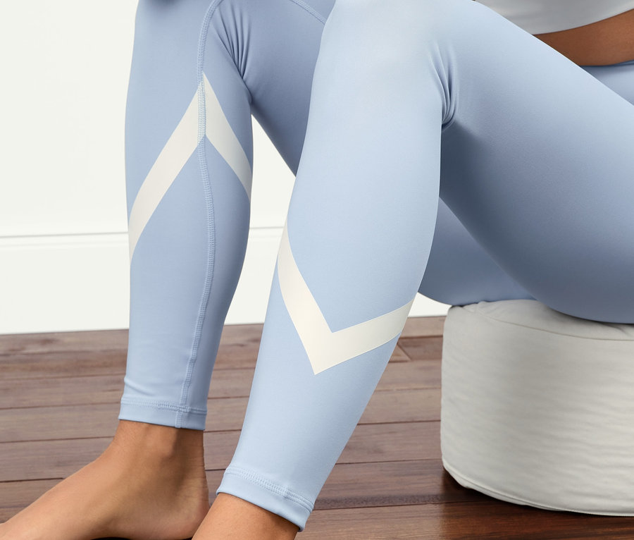 Kobieta siedzi na podłodze w błękitnych legginsach sportowych »Soft Touch«.