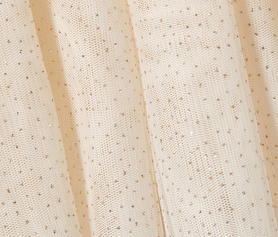 Zbliżenie na kremową tiulową spódniczkę dla dzieci z delikatnymi złotymi kropkami.