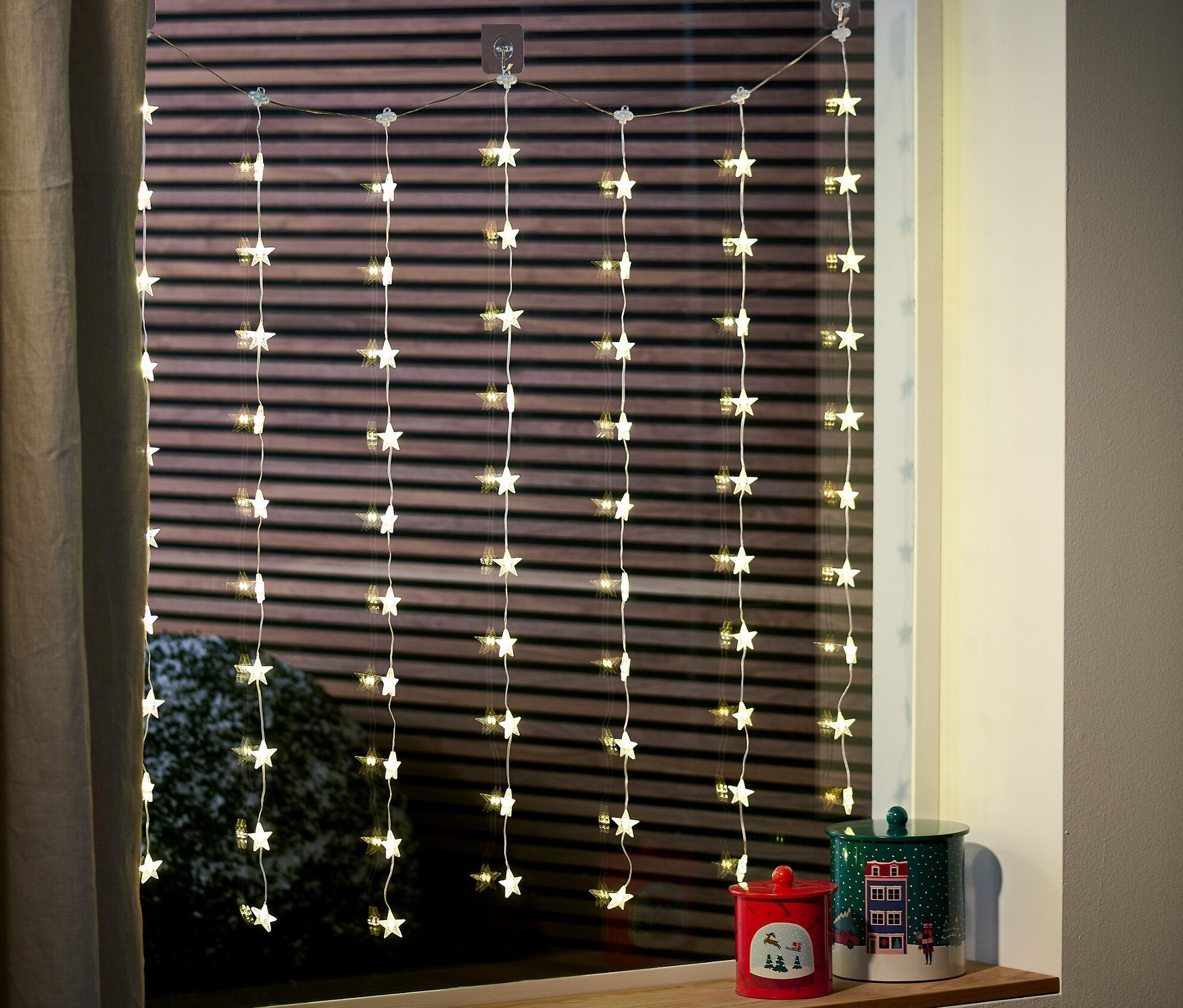 Kurtyna LED z gwiazdami wisi w oknie.