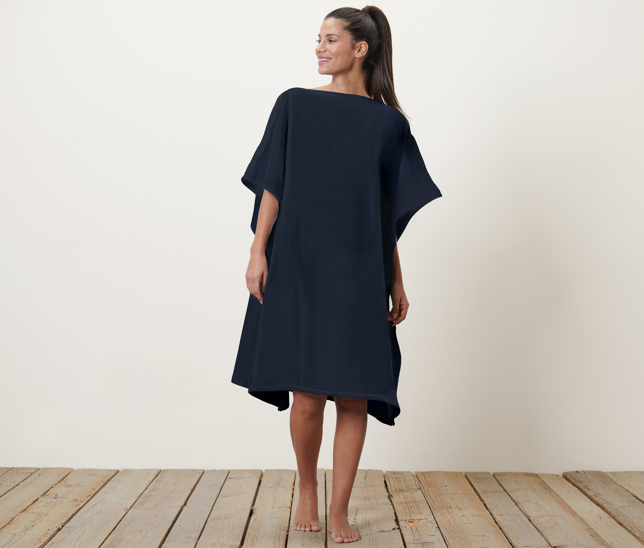 Kobieta pozuje w ręczniku-ponczo 2 w 1.