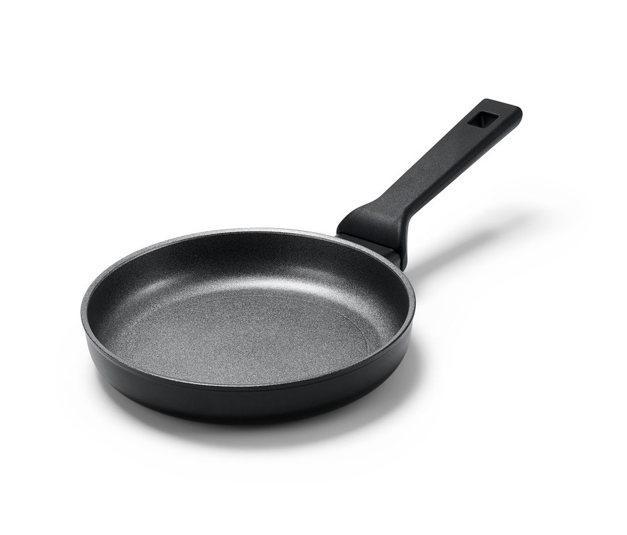 Czarna, aluminiowa patelnia profesjonalna o średnicy około 20 cm na białym tle.