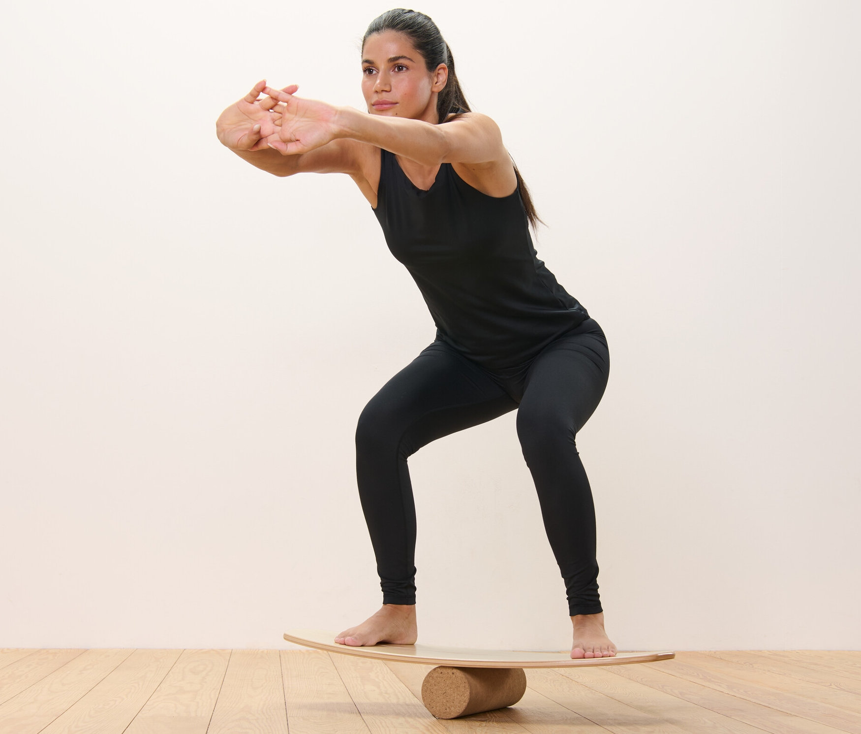 Kobieta robi przysiady na desce równoważnej.
