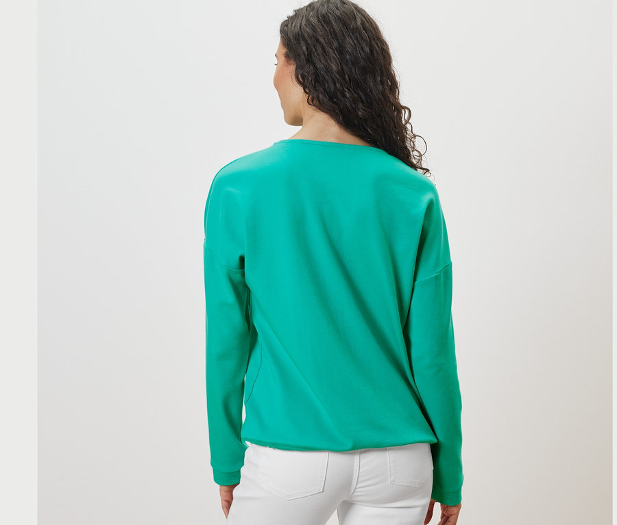 Widok z tyłu na kobietę z ciemnymi włosami w turkusowej bluzie.