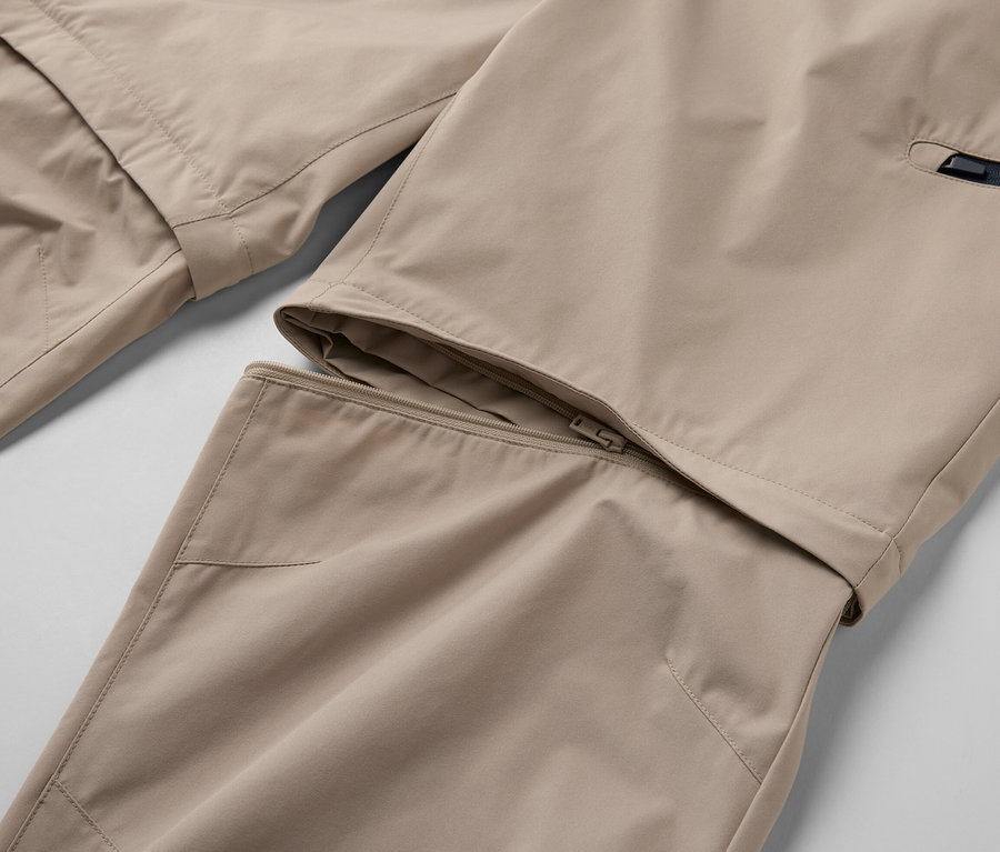 Szczegół beżowych spodni funkcyjnych 2 w 1 z zamkiem błyskawicznym.