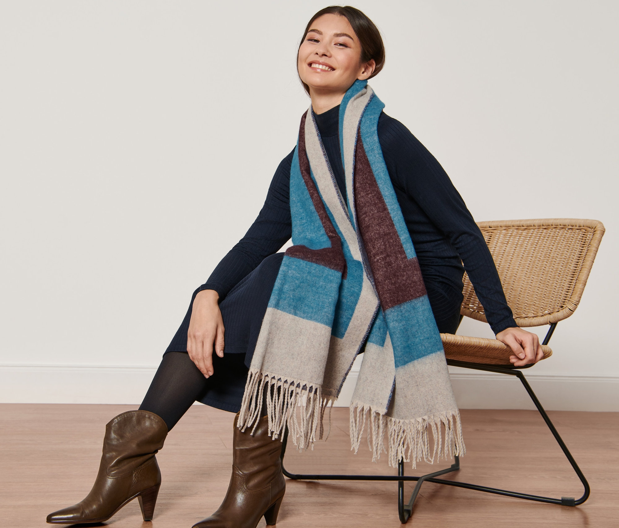 Kobieta siedzi na krześle i ma na sobie tkany szal.