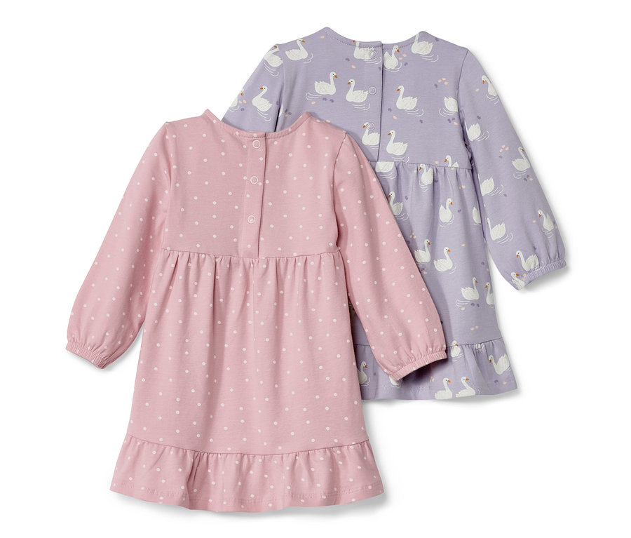 Dwie dżersejowe sukienki: jedna różowa w białe kropki i jedna fioletowa we wzór z łabędziami.