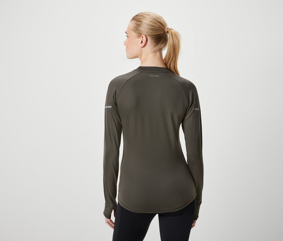 Widok z tyłu kobiety z blond włosami związanymi w kucyk, ubranej w oliwkowozieloną koszulkę z długim rękawem i czarne legginsy.