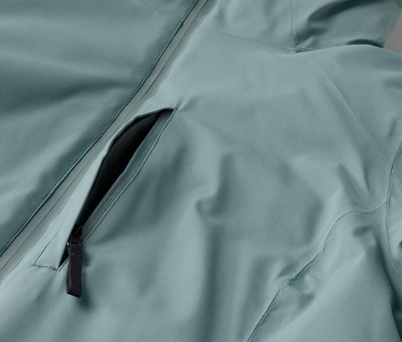 Zbliżenie na jasno-niebieską kurtkę z czarnym zamkiem błyskawicznym.