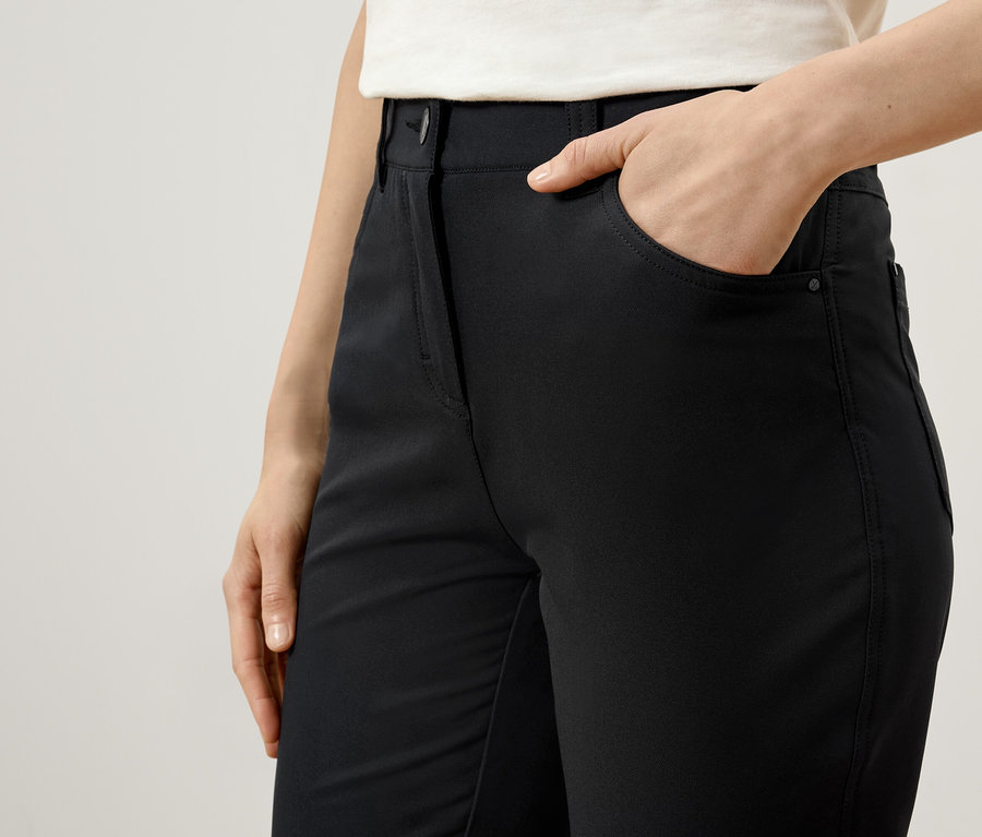 Kobieta trzyma rękę w kieszeni czarnych spodni.