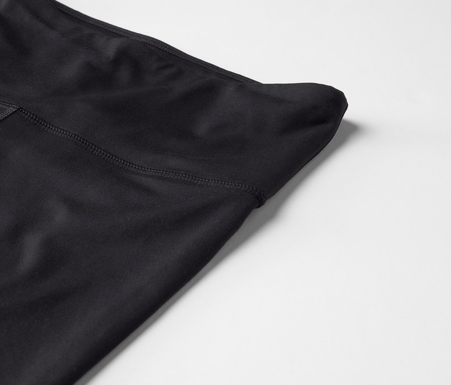 Zbliżenie czarnych legginsów z wysokim stanem na białym tle.