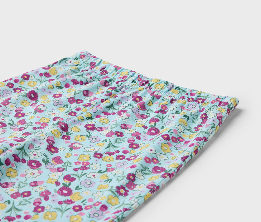 Szczegół jasnoniebieskich spodni w kwiatowy wzór z elastycznym pasem.