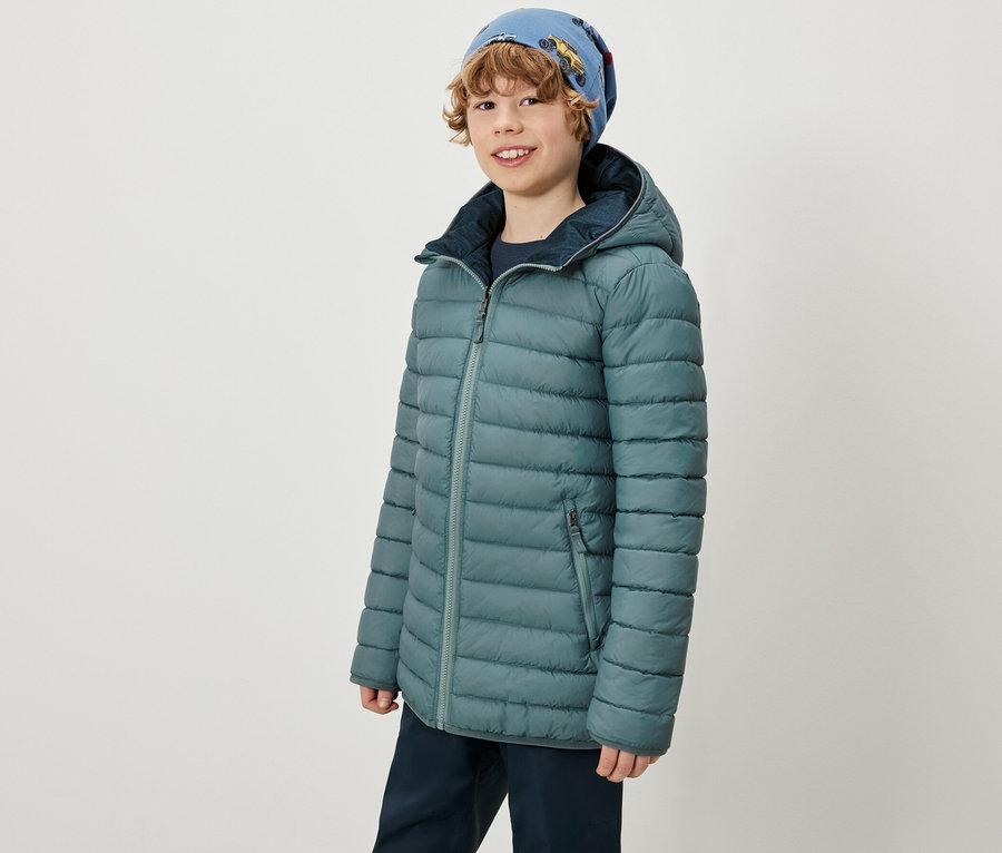 Chłopiec ma na sobie kurtkę 2-w-1 Kinder Softshell i Steppjacke oraz niebieską czapkę.