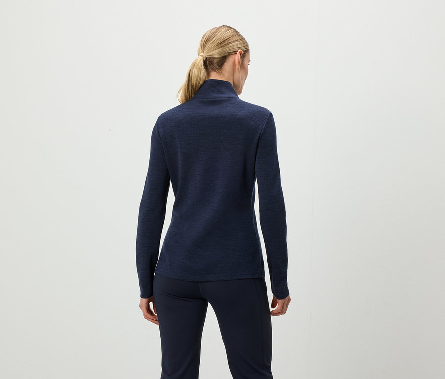 Z tyłu widać kobietę z blond włosami związanymi w koński ogon, ubraną w granatową bluzkę z długim rękawem i granatowe spodnie.