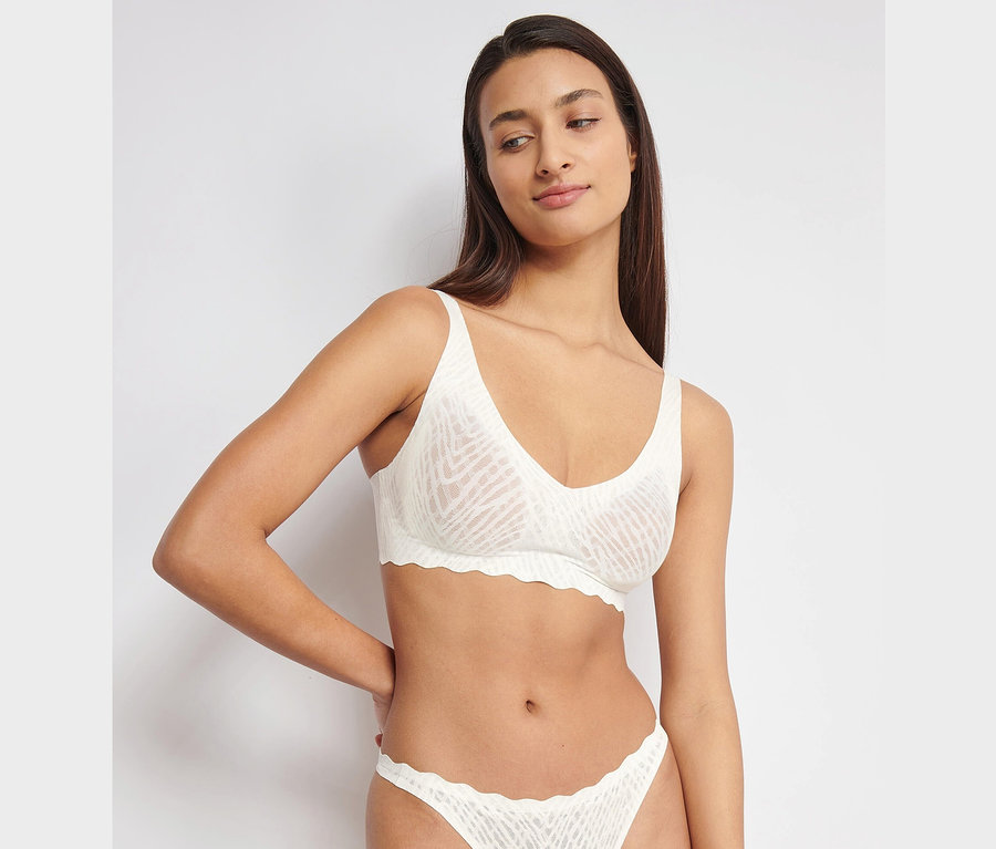 Kobieta ma na sobie miękki biustonosz sloggi ZERO Feel Bliss, silk white i pasujące figi.