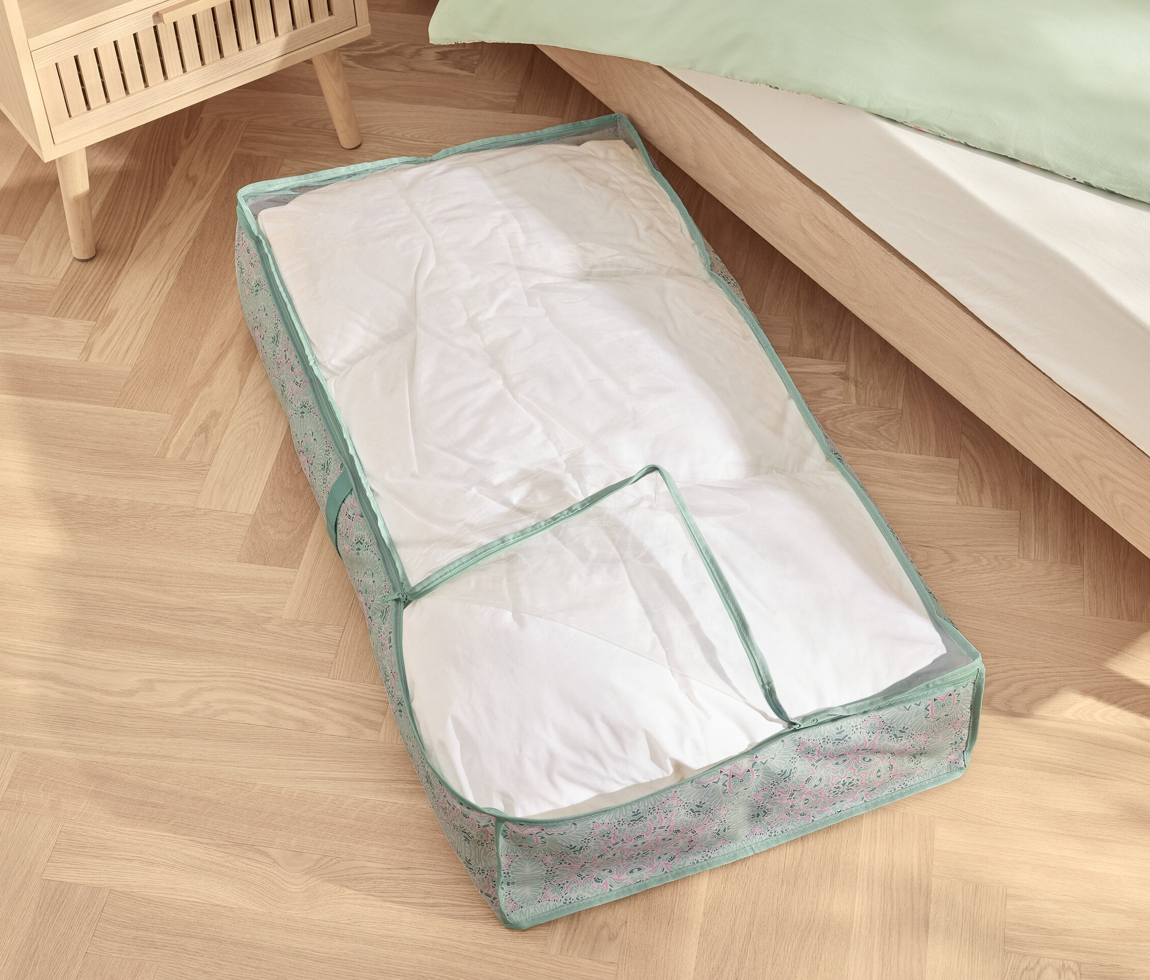 Pod łóżkiem leży komoda pod łóżko z białą kołdrą.