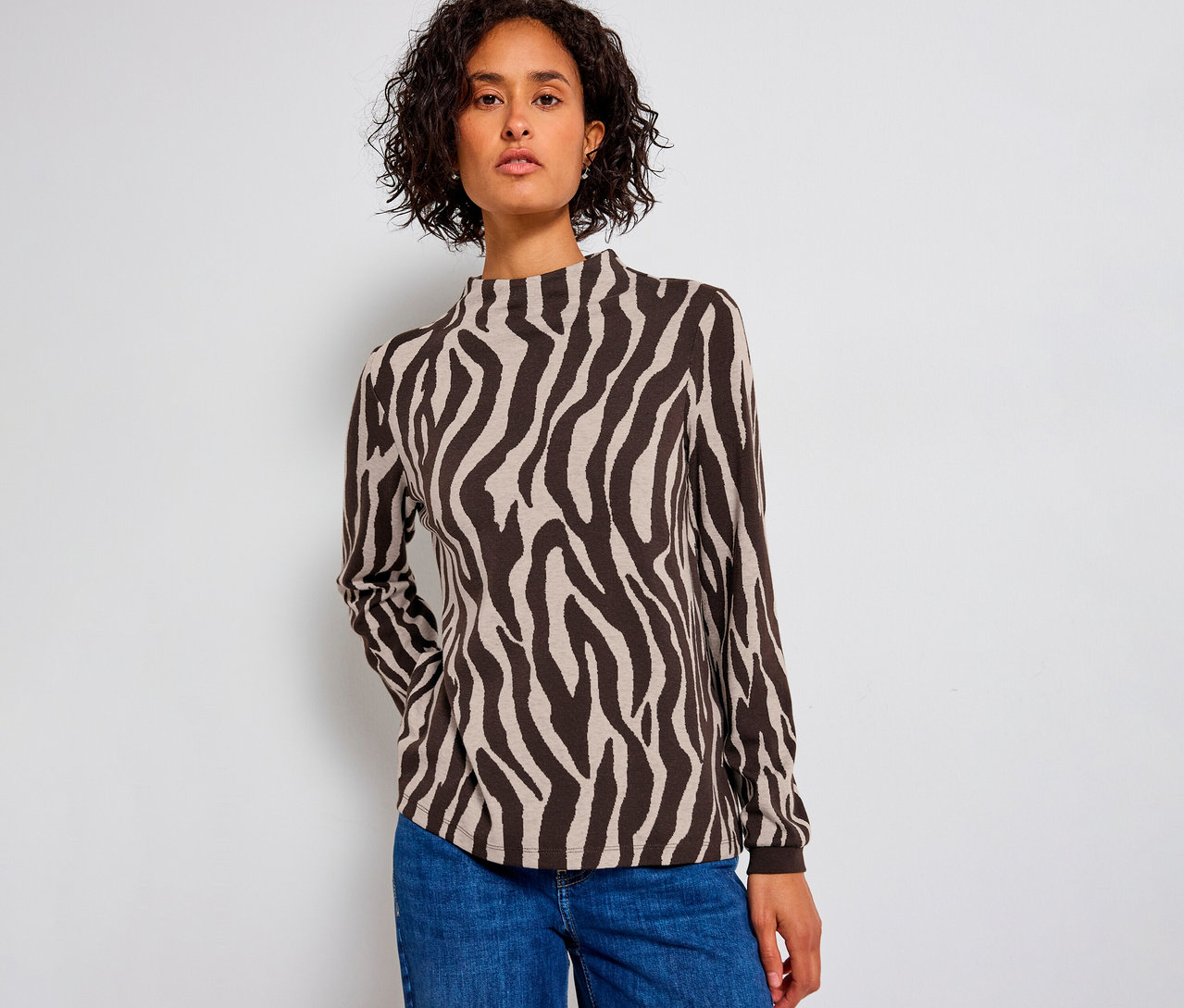 Kobieta ma na sobie żakardową koszulkę Street One w zebrę i niebieskie dżinsy.
