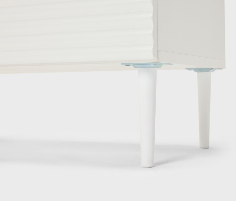 Szczegółowy widok białego mebla ze stożkowymi nogami.