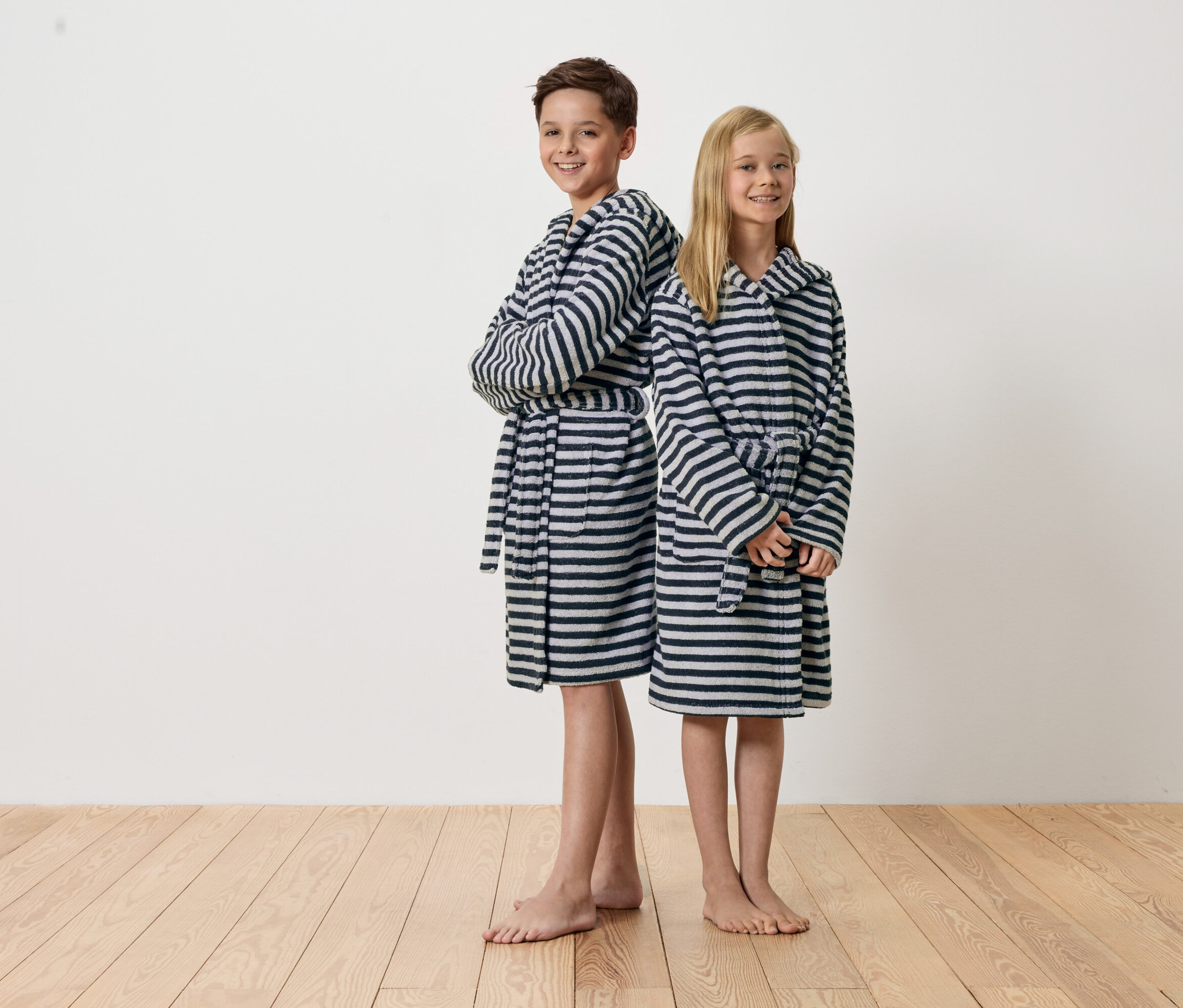 Chłopiec i dziewczynka stoją do siebie plecami, ubrani w szlafrok w paski.