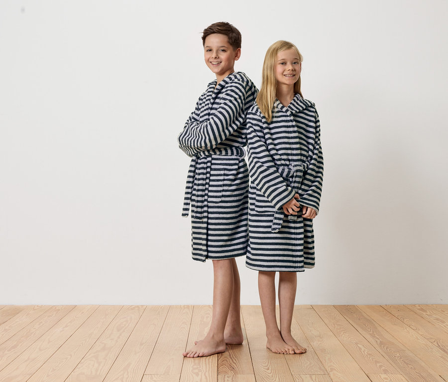 Chłopiec i dziewczynka stoją do siebie plecami, ubrani w szlafrok w paski.