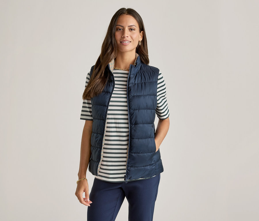 Kobieta w granatowej kamizelce nałożonej na koszulkę z półdługim rękawem, w zielone paski.