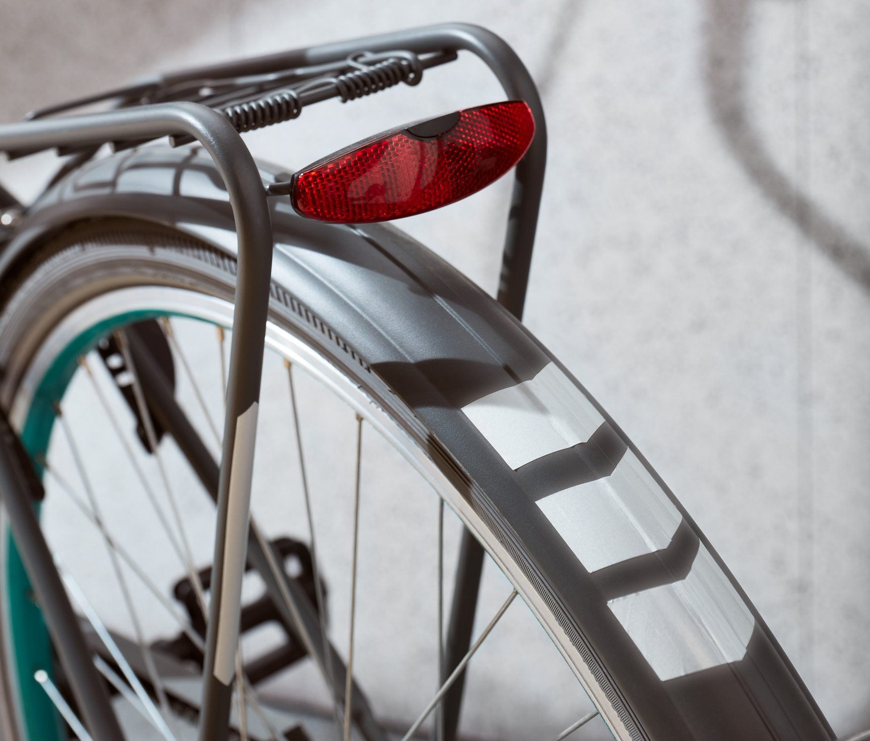 Zbliżenie na tylne koło roweru z czerwonym światłem i naklejkami odblaskowymi.